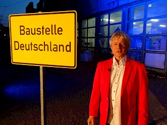 Jürgen Becker vor dem Baustelle-Deutschland-Schild